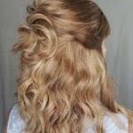 Blonde hair styled in loose curls with a half-updo.