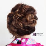 Intricate updo hairstyle with soft curls and highlights.