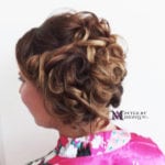 Curly updo hairstyle with highlights viewed from the side.