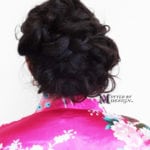 Back view of an intricate braided updo hairstyle on dark hair.