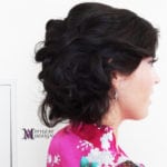 Side profile of a woman with dark, styled hair in an updo.