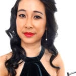 Portrait of a woman with black wavy hair and red lipstick.