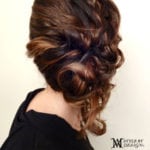 Intricately braided updo hairstyle with loose curls.