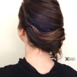 A woman with dark hair styled in a twisted low bun.