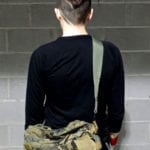 Person with short hair wearing a black shirt and camouflage pants, facing away.