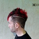 Side profile of a man with red mohawk and shaved designs.