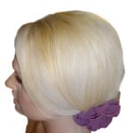 Side profile of a woman with platinum blonde hair and a purple flower accessory.