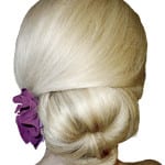 Elegant blonde hair styled in a low bun with a purple flower accessory.