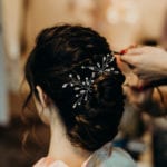 A woman styling her hair with a decorative hairpin.