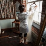 Woman standing near a window, adjusting curtains.