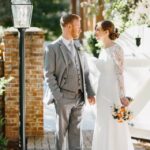 A bride and groom holding hands outdoors.