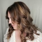 A woman with wavy brown hair looking down.