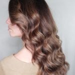 Side profile of a woman with long, wavy brown hair.