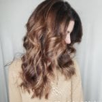 Woman with long, wavy brown hair styled in loose curls.