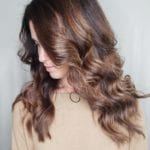 A woman with wavy brown hair looking down.