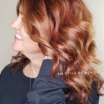 A woman with wavy, reddish-brown hair smiling.