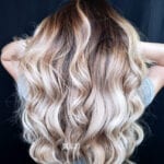 Long wavy blonde hair with dark roots on a person.