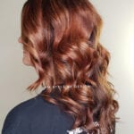 Wavy auburn hair cascading down the back.