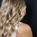Blonde wavy hair cascading over a shoulder against a black backdrop.