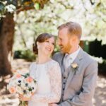 A bride and groom smiling lovingly under a tree.
