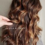 Long wavy hair with brown and caramel highlights.