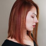 Profile of a woman with straight auburn hair and closed eyes.
