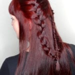 A woman with long red hair styled in a thick braid.