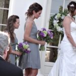 Bridesmaids in gray dresses holding bouquets at a wedding.