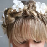 Close-up of a braided hairstyle adorned with white flowers.