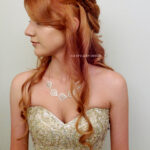 Woman with long red hair in an elegant strapless dress looking to the side.