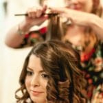 A woman getting her hair curled by a stylist.