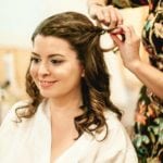 A woman getting her hair styled, smiling gently.