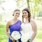 Two women in wedding attire smiling outdoors.