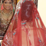 Bride covered with a red veil during a wedding ceremony.