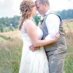 Bride and groom embracing outdoors in a field.