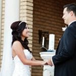 Bride and groom holding hands, smiling at each other.