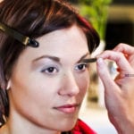 A woman getting her eyebrows shaped with a brush.