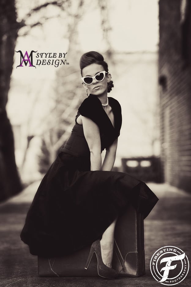 A stylish woman in vintage attire posing outdoors.