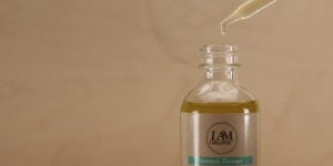 A dropper releasing oil into a small glass bottle.