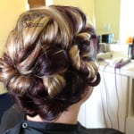 Intricately styled updo with soft curls and highlights.