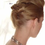 A woman with blonde hair styled in an elegant updo wearing a necklace.