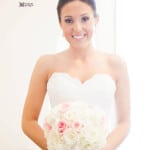 A bride in a strapless white wedding dress holding a bouquet of white and pink flowers.