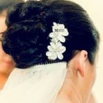 Bridal hairstyle with a white floral hair accessory.