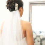 Bride with white veil and floral hair accessory seen from behind.