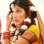 A woman in traditional Indian attire adjusting her earring.