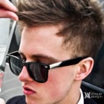 Close-up of a young man wearing black sunglasses and styled hair.