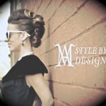 A stylish woman with retro hair and sunglasses leaning against a brick wall.