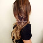 Long wavy brown hair with blonde ombre highlights.