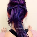 Person with vibrant purple hair styled in a half-updo with loose strands.