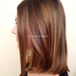 Side view of a woman with shoulder-length brown hair with highlights.